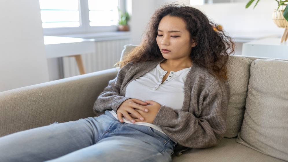 woman lying on a couch holding her stomach